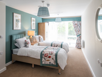 Inside the modern spare room of the show home with twin beds looking through large window