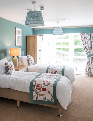 Inside the modern spare room of the show home with twin beds looking through large window 