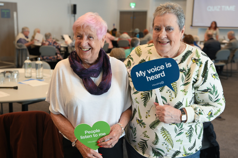 Two residents posing and smiling holding influencer signs
