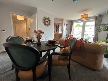 A living room inside an apartment at Askern Vale featuring a dining table with chairs, sofa and patio doors