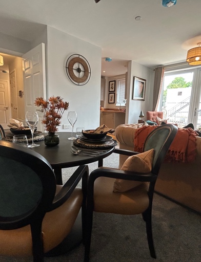 A living room inside an apartment at Askern Vale featuring a dining table with chairs, sofa and patio doors