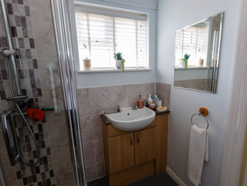 A bathroom with sink under the window and shower