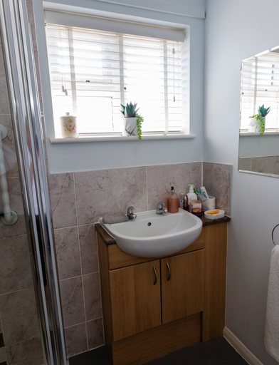 A bathroom with sink under the window and shower 
