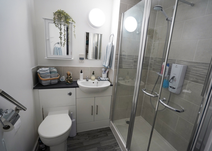 A newly refurbished bathroom with sink, toilet and tiled shower. 
