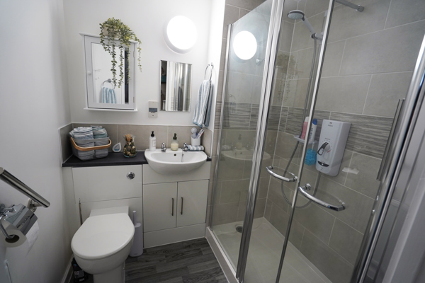 A newly refurbished bathroom with sink, toilet and tiled shower. 