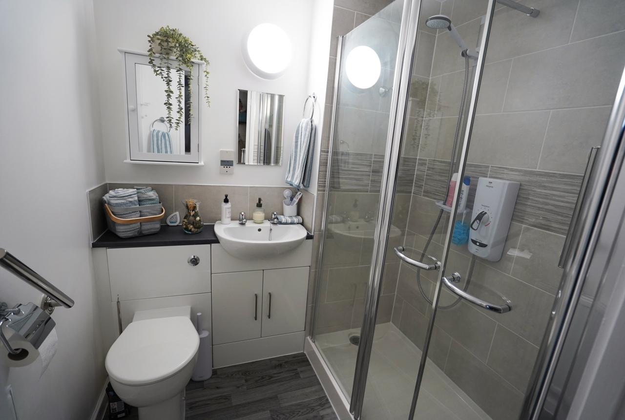 A newly refurbished bathroom with sink, toilet and tiled shower. 