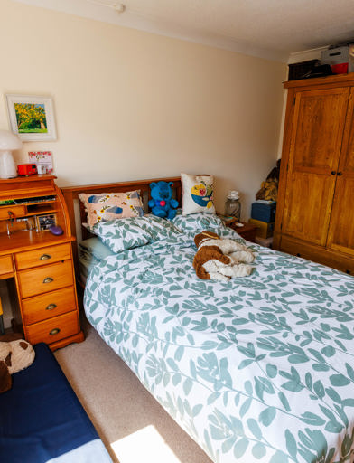 Spacious bedroom with a queen-sized bed, triple-door wardrobe, and writing desk with drawers.