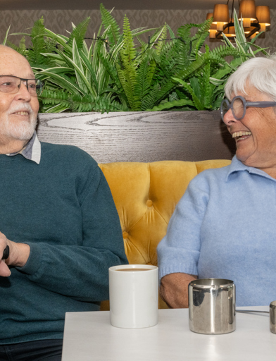 A couple smiling and laughing while having a cup of tea 