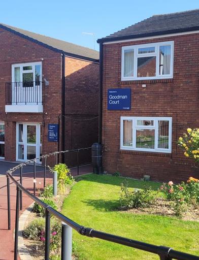 A photo of the outside area of Goodman Court with car parking spaces and garden area 