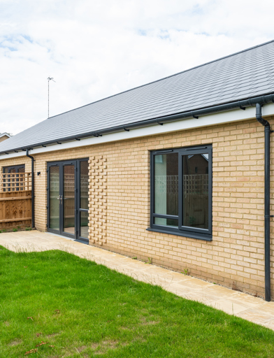 Rear of the show home bungalow with grassed garden area and small path and patio 