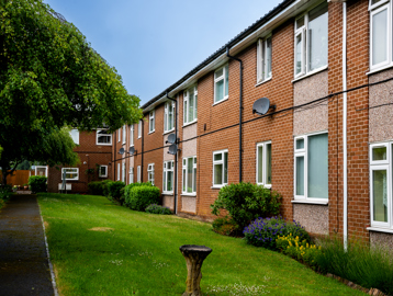 External photo of the building with neat and tidy garden and blue sky