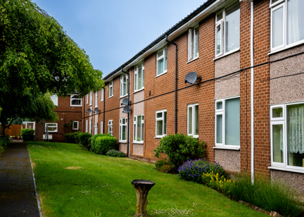 External photo of the building with neat and tidy garden and blue sky
