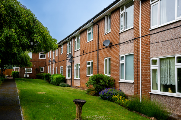 External photo of the building with neat and tidy garden and blue sky