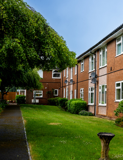 External photo of the building with neat and tidy garden and blue sky 