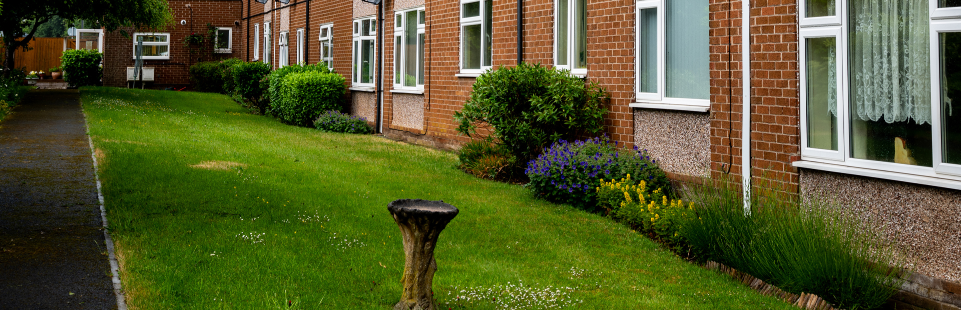 External photo of the building with neat and tidy garden and blue sky