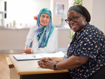 Receptionist and resident smiling at camera
