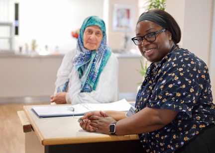 Receptionist and resident smiling at camera