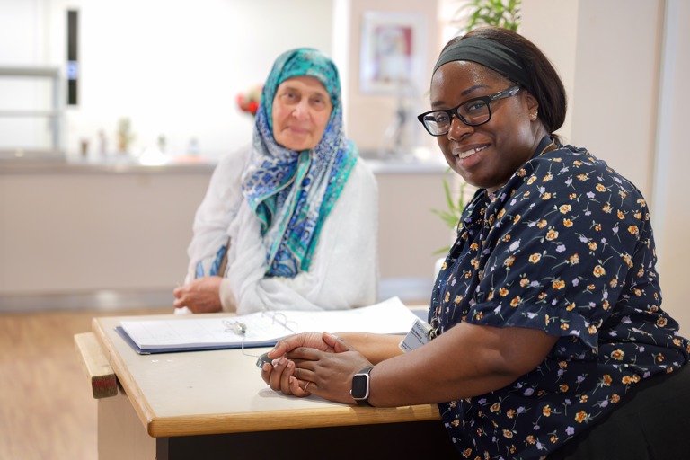 Receptionist and resident smiling at camera