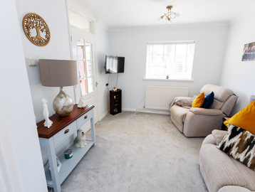 A lightly-decorated living room with window, sofa, TV and furniture