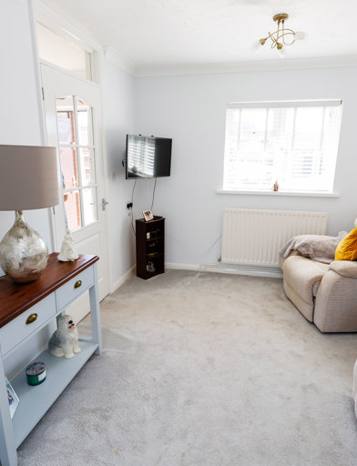 A lightly-decorated living room with window, sofa, TV and furniture 