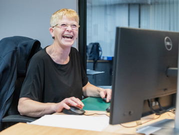 A Housing 21 employee laughing as she works at her computer