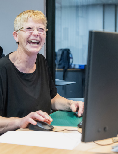 A Housing 21 employee laughing as she works at her computer 