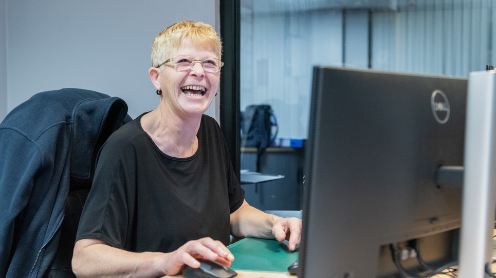 A Housing 21 employee laughing as she works at her computer