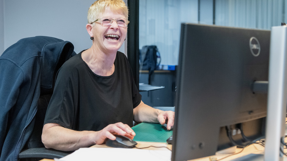A Housing 21 employee laughing as she works at her computer