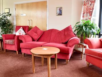 Resident's lounge area with red sofa seating and tables