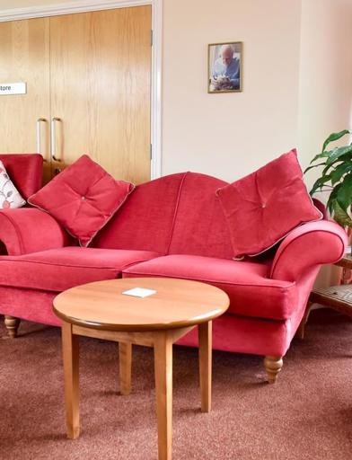 Resident's lounge area with red sofa seating and tables 