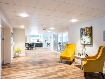 Communal corridor with two large yellow armchairs looking down towards the cafe/ bistro