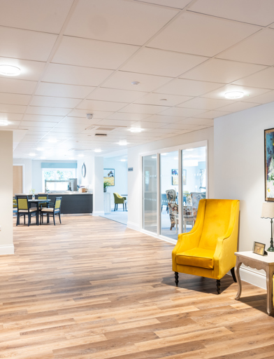 Communal corridor with two large yellow armchairs looking down towards the cafe/ bistro 