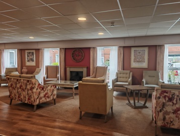 A lounge with a mix of flora decorated sofas, armchairs and coffee tables around a fireplace