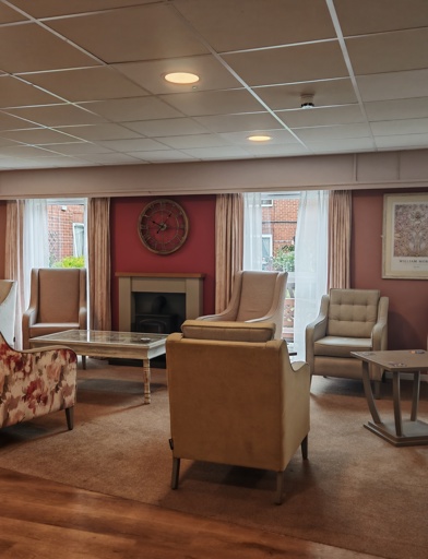 A lounge with a mix of flora decorated sofas, armchairs and coffee tables around a fireplace 