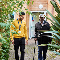 Resident and employee walking in the garden