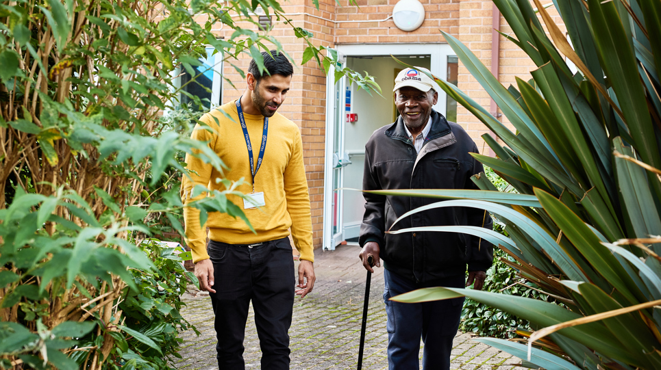 Resident and employee walking in the garden