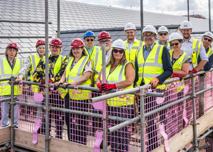 Group picture of employees and construction partners standing on a roof of a new Housing 21 development