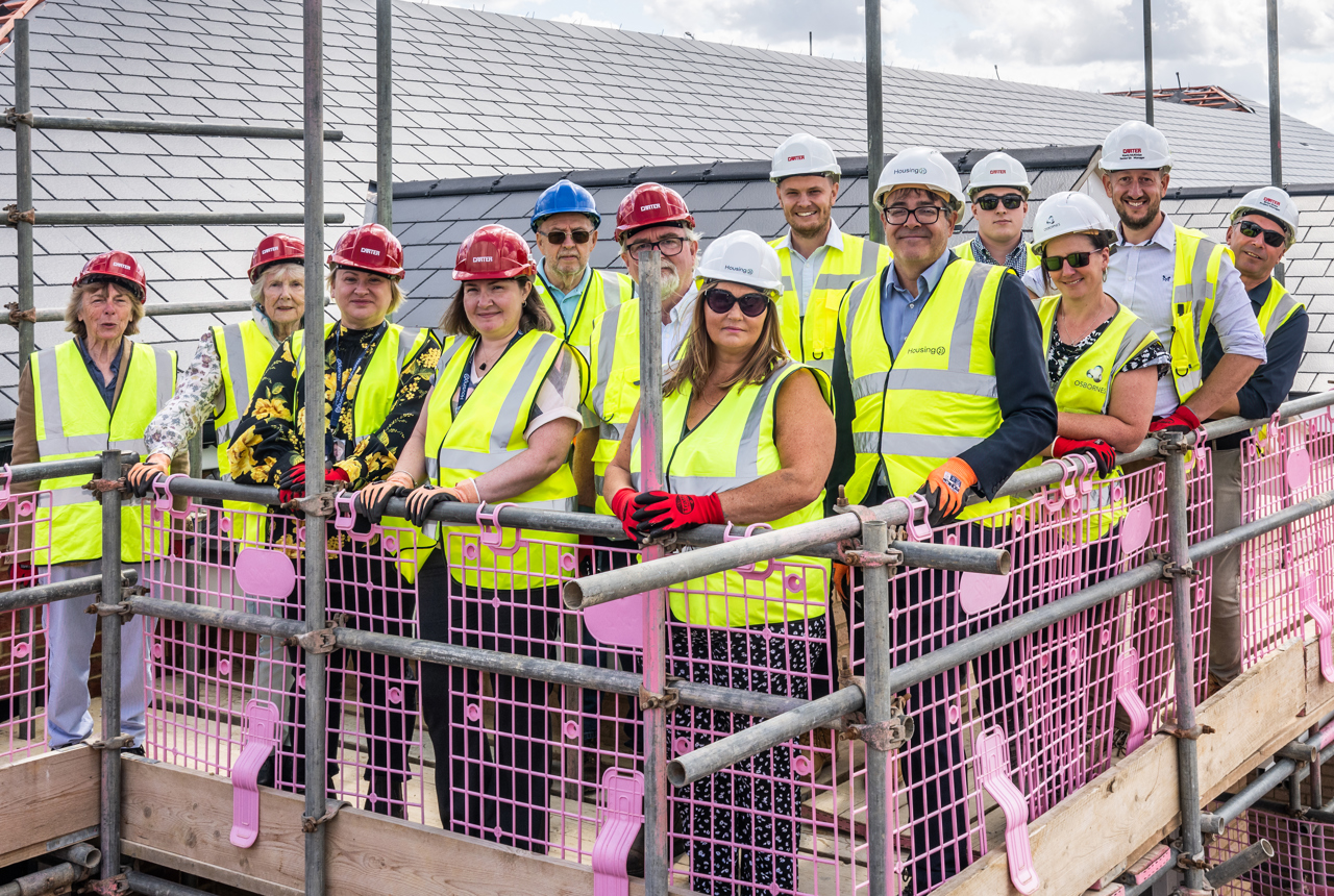 Group picture of employees and construction partners standing on a roof of a new Housing 21 development