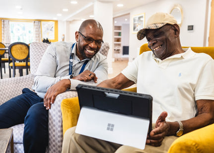 Resident and employee sitting down using a laptop