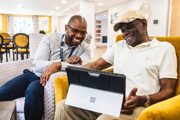 Resident and employee sitting down using a laptop