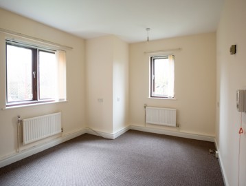 An empty bedroom in an apartment with a single and double window