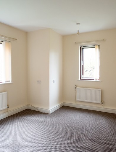 An empty bedroom in an apartment with a single and double window