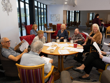 A group of residents sat around a table smiling and laughing enjoying a quiz
