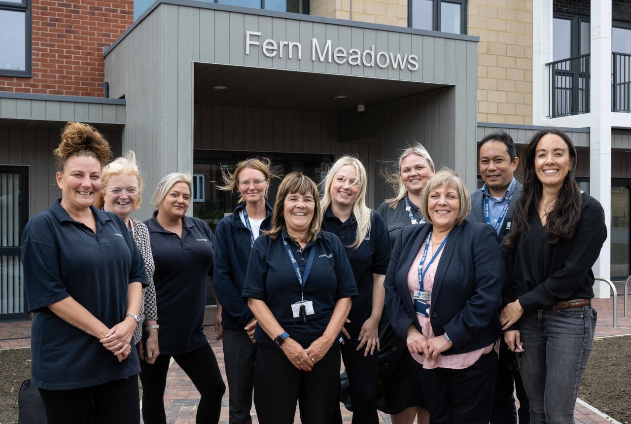 A group of Housing 21 colleagues and partners positioned at the front entrance outside Fern Meadows