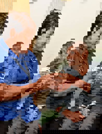 Female care worker handing male resident a drinks cup