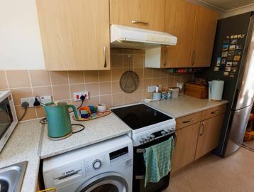Kitchen with fitted units, storage space, washing machine, small double oven, and standing fridge freezer.