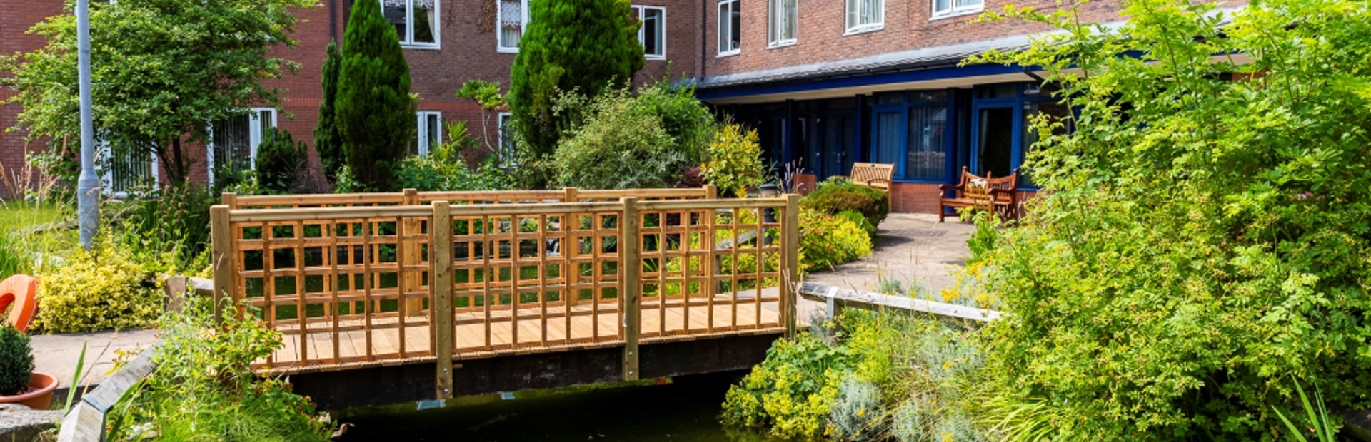 A three storey residential property overlooks a pond with a bridge across it