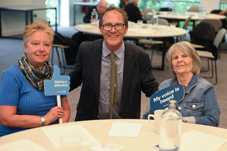 Chief Executive Bruce Moore sat between residents smiling and holding influencer signs