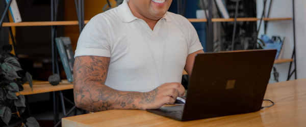 A employee sat at a table on a laptop smiling