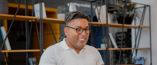A employee sat at a table on a laptop smiling